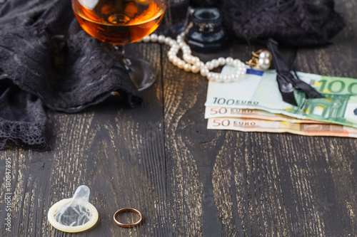 Wedding ring and condom with money on back, adultery concept