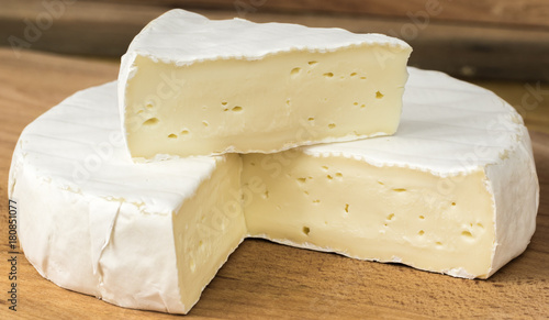 Round of Camembert cheese brie with triangle cut out placed on top .