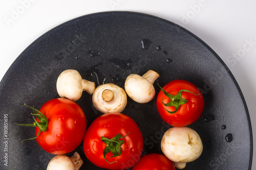 fresh tomatoes and mushrooms - champignons on black plate
