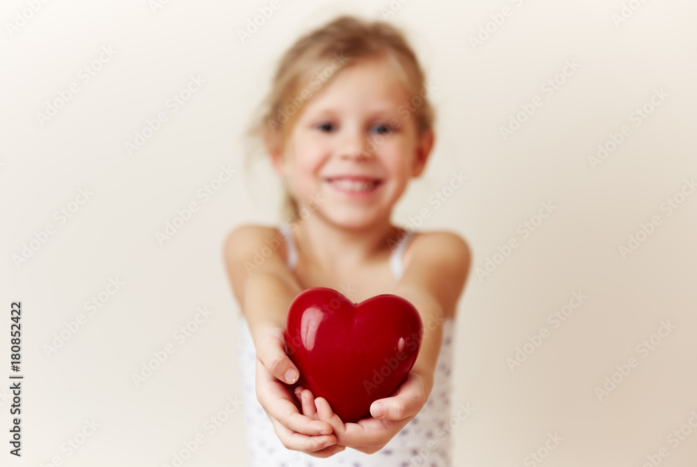 Beautiful smiling girl giving red heart as symbol of love and happiness. Beautiful smiling girl giving red heart as symbol of love and happiness.