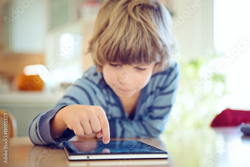 Little boy using digital tablet. Selective focus on child's finger, shalow depth of field.
