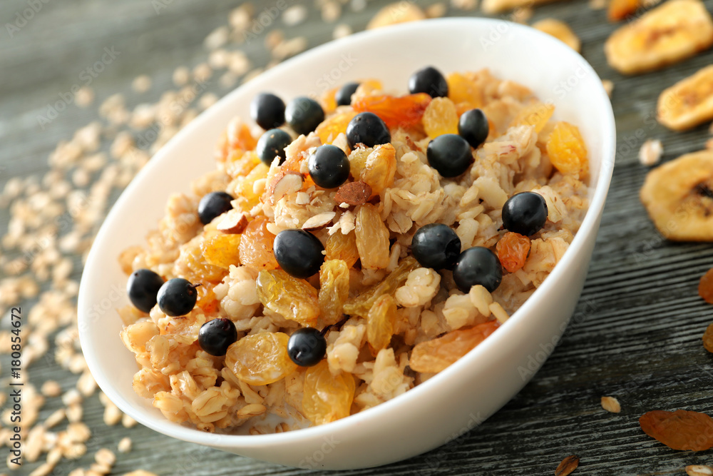 Tasty oatmeal with berries and dried fruits in bowl on table, closeup Tasty oatmeal with berries and dried fruits in bowl on table, closeup