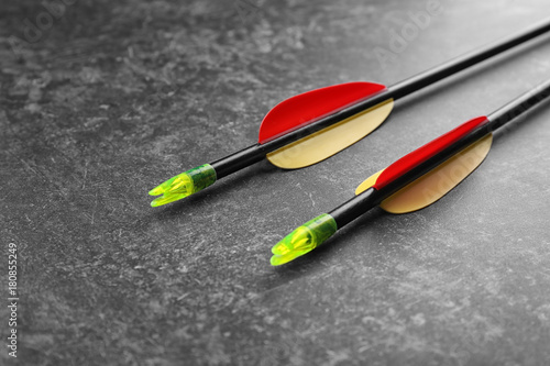 фотографія Two archery arrows with red and yellow fletching and green nocks on dark texture