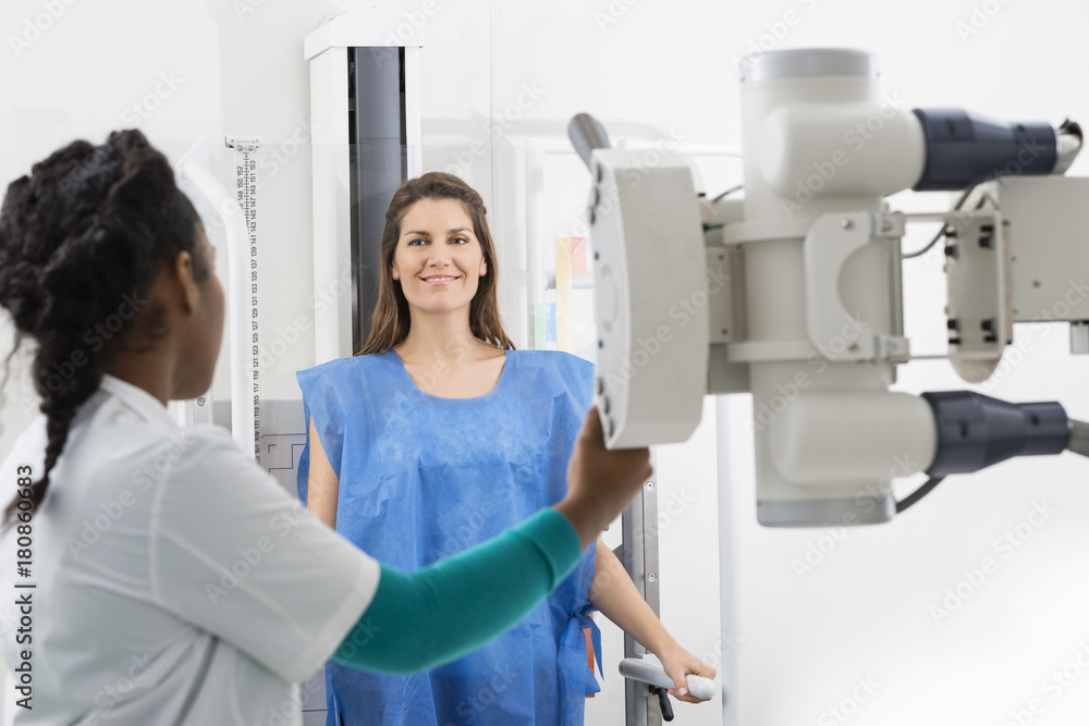 Radiologist Adjusting X-ray Machine On Female Patient At Hospita Radiologist Adjusting X-ray Machine On Female Patient At Hospita