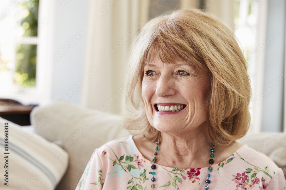Smiling Senior Woman Sitting On Sofa At Home Smiling Senior Woman Sitting On Sofa At Home
