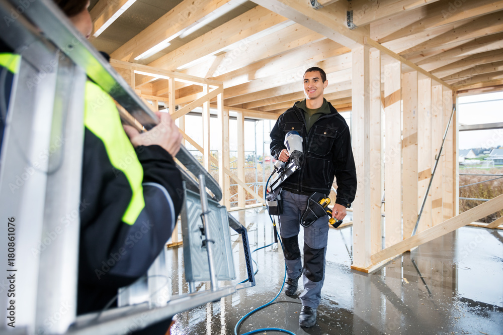 Carpenter Holding Drill Machine While Looking At Colleague Carry