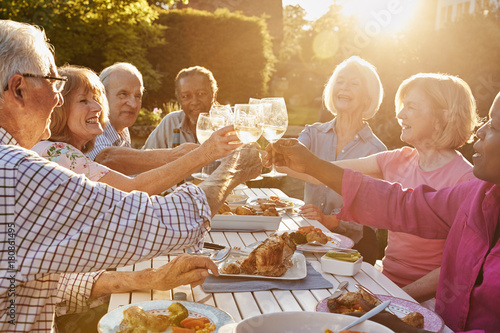 Photography Group Of Senior Friends Making A Toast At Outdoor Dinner Party