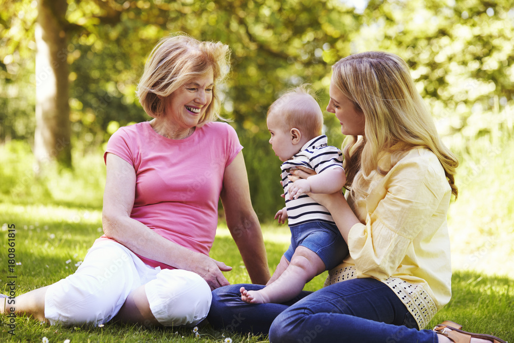 Grandmother And Mother Playing With Baby Son Outdoors In Garden Grandmother And Mother Playing With Baby Son Outdoors In Garden