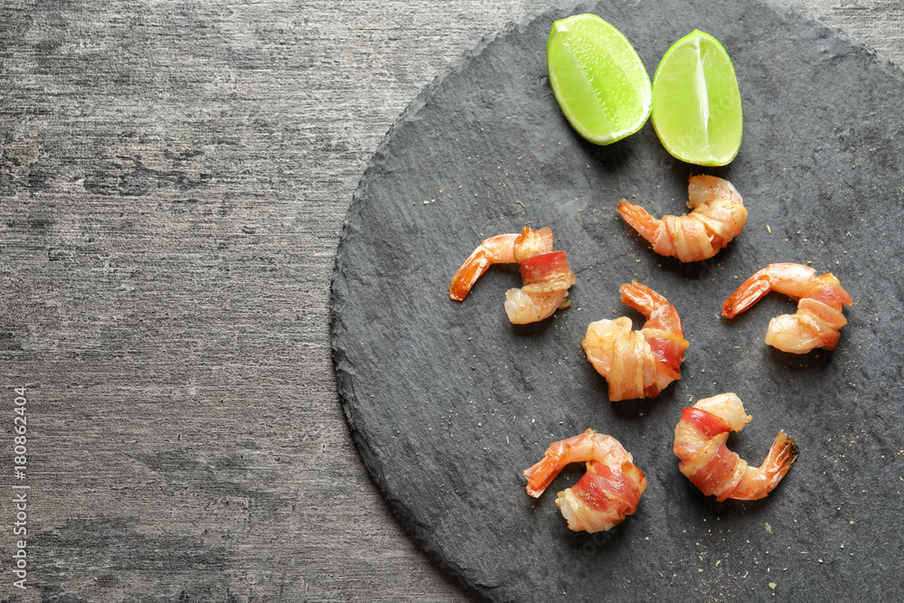 Slate plate with bacon-wrapped shrimps on table