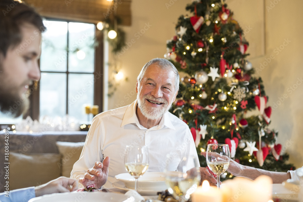 Smiling senior man looking at adult son at Christmas dinner table Smiling senior man looking at adult son at Christmas dinner table