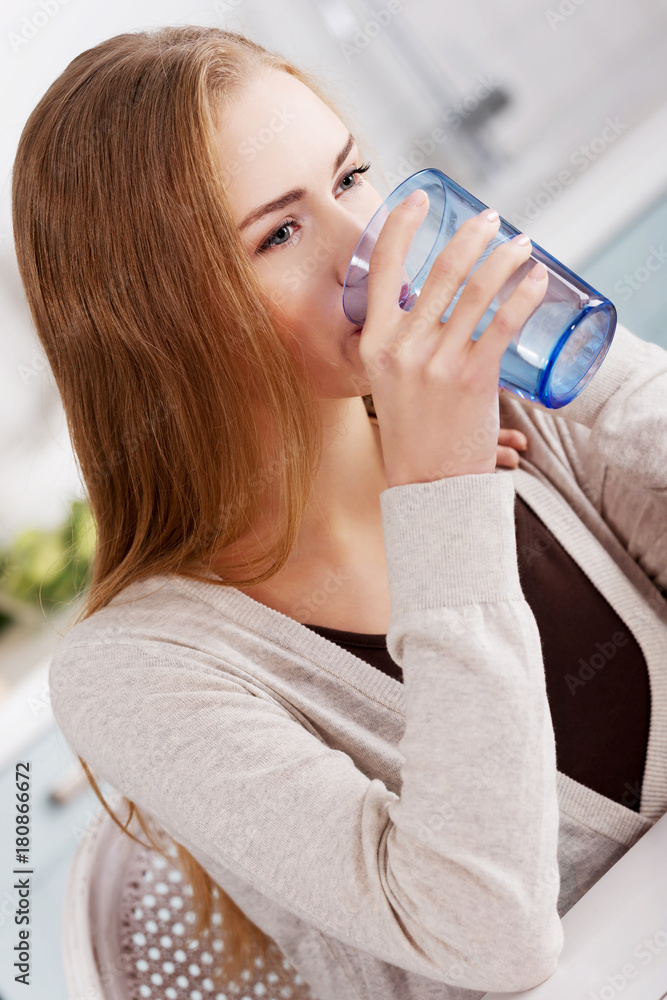 Beautiful caucasian woman is sitting in the kitchen and drinking Beautiful caucasian woman is sitting in the kitchen and drinking