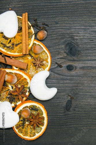 Christmas background: white gingerbread cookies, dried orange, cinamon, anise and cloves on dark brown wooden plank, copy space photo