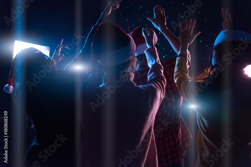 Group Asian young friends dancing Together party with Disco lights celebrating Christmas at dark home