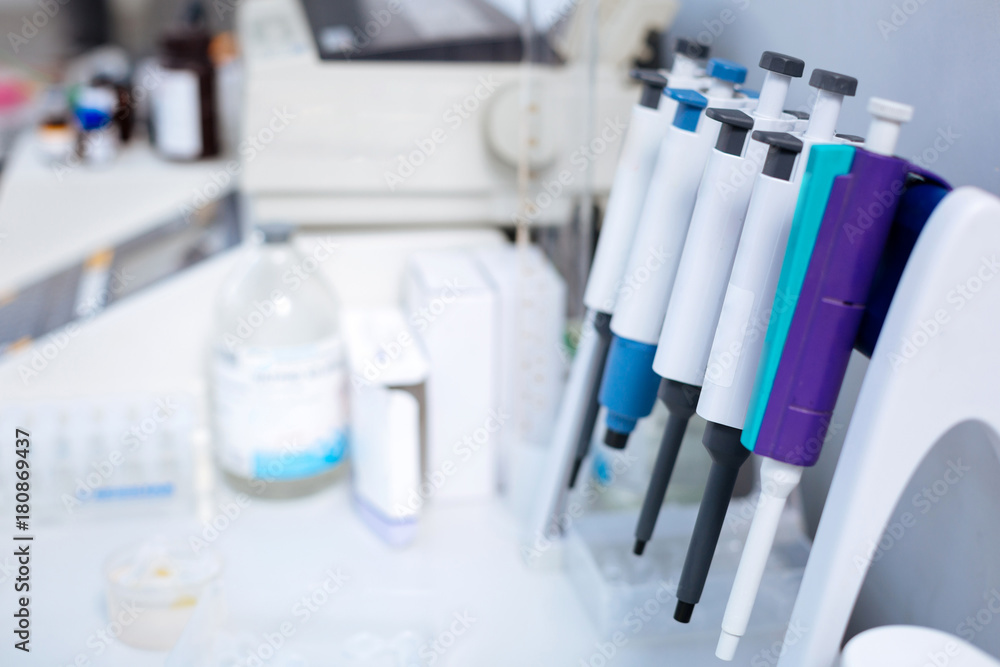 Get tested. Clean current medical pipettes affixed to the stand hanging above the table while medications placed on the background 
