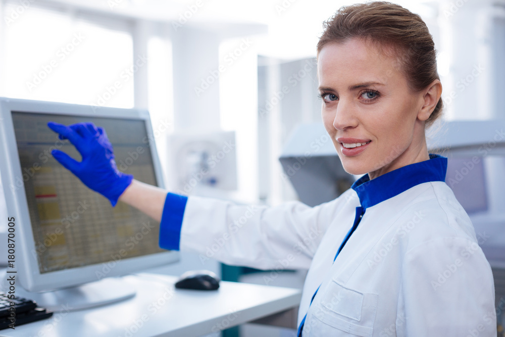 One more step. Portrait of female scientist transferring data from experiment looking straight while holding her hand near the screen 