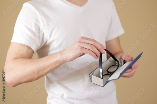 Man in white t shirt hand puts glasses in case with isolated background