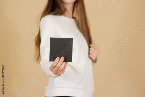 Girl showing blank black square flyer brochure booklet. Leaflet presentation. Pamphlet hold hands. Woman show clear offset paper. Sheet template. Booklet design sheet display read first person