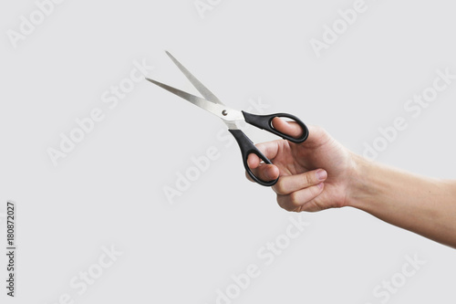 Foto Scissors in hand. Isolated on grey background