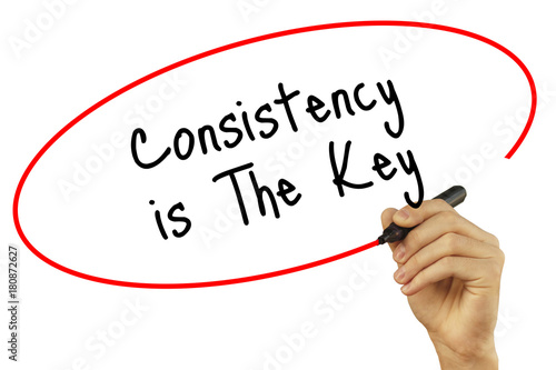 Man Hand writing Consistency is The Key with black marker on visual screen. Isolated on white background. Business, technology, internet concept. Stock Photo