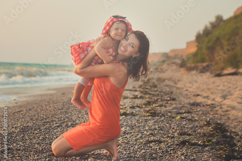 Hokum tender scene of beautiful adorable young mother enjoy life time summer vacation with her little baby girl daughter on sand beach.Family emotions together