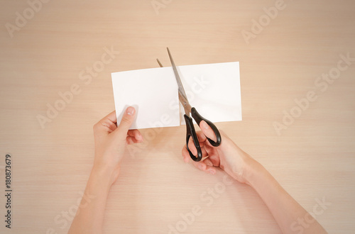 Hands cut white paper with scissors.