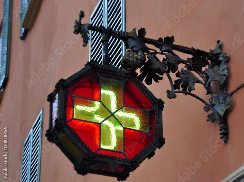 Schmiedeeiserne, rot-gelb verglaste Straßenlaterne an einer Apotheke in der Altstadt von Bologna