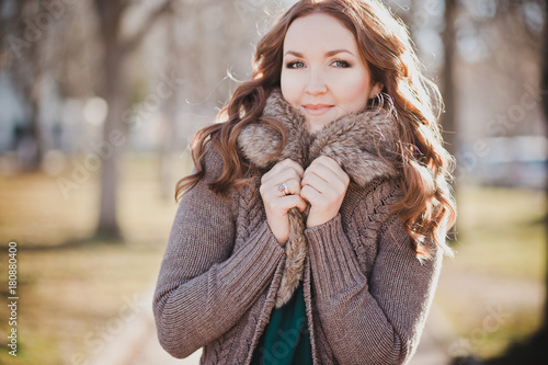 Mysterious adorable young brunette lady portrait with cute face and seducing lips professionally posing sit for camera wearing cosy warm designer clothes with fur in autumn spring central park photo
