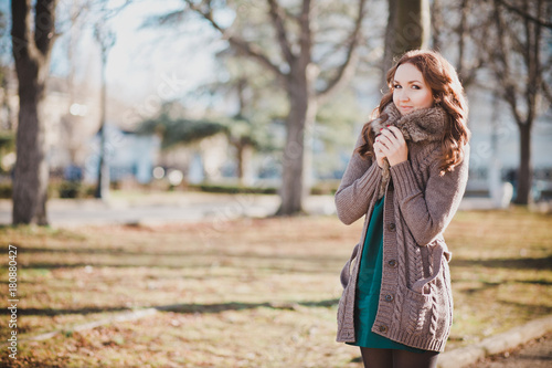 Mysterious adorable young brunette lady portrait with cute face and seducing lips professionally posing sit for camera wearing cosy warm designer clothes with fur in autumn spring central park photo