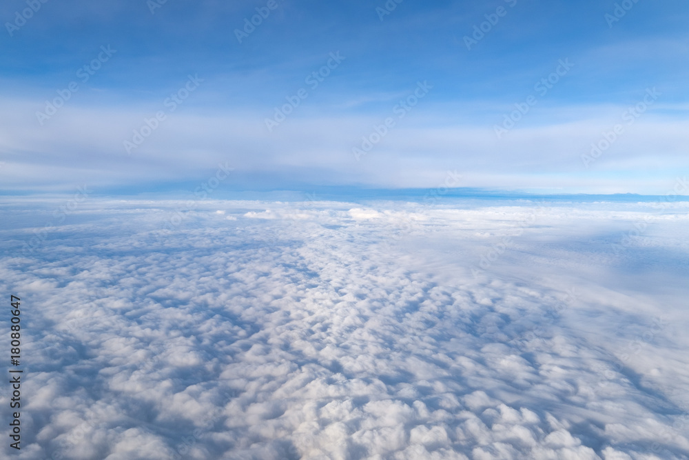 View from airplane window above the clouds with blue sky and cloudscape in sunlight morining. white wispy cirrus and cirrostratus clouds View from airplane window above the clouds with blue sky and cloudscape in sunlight morining. white wispy cirrus and cirrostratus clouds