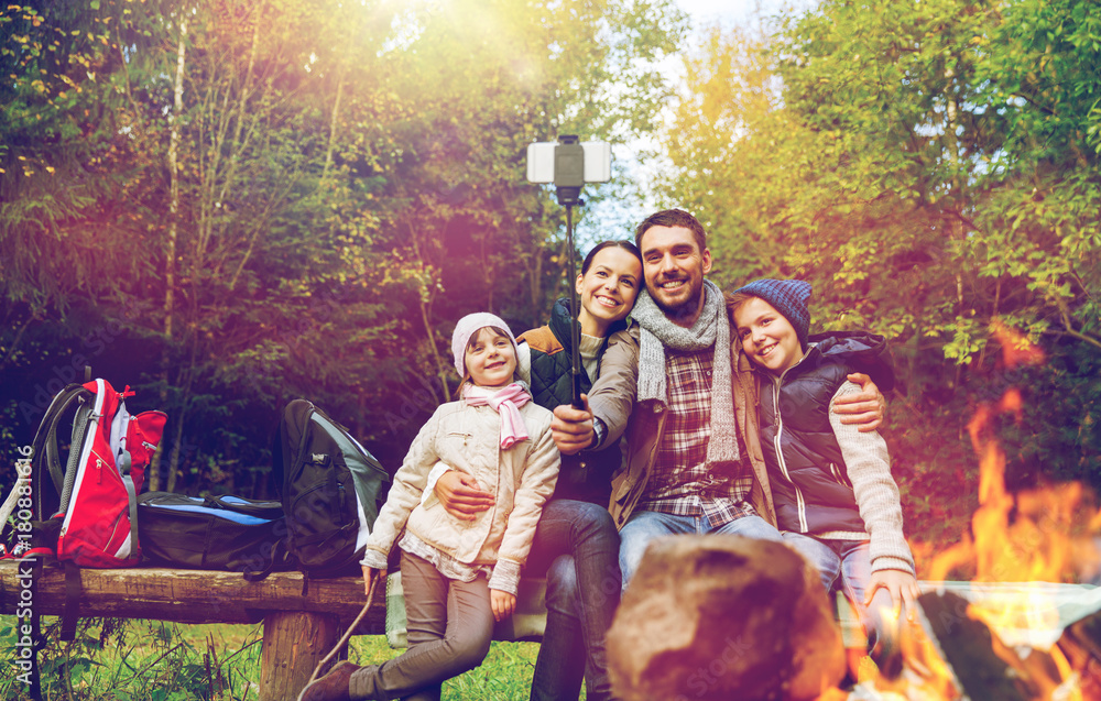 family with smartphone taking selfie near campfire