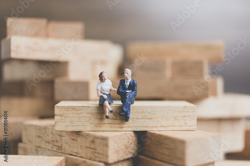 Miniature people : Business People sitting on wood block with wooden background
