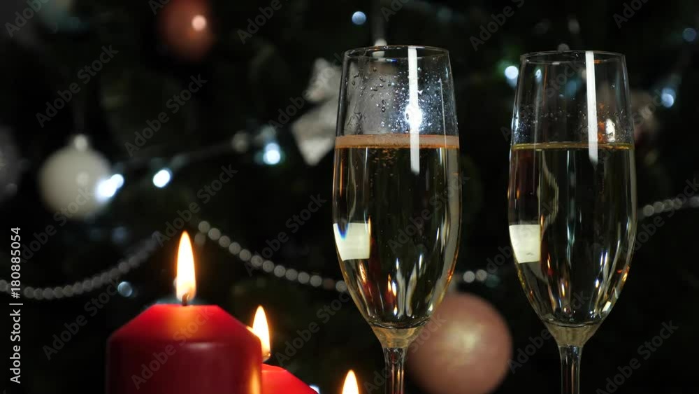 champagne is poured into a glass on christmas tree background wuth red candles champagne is poured into a glass on christmas tree background wuth red candles