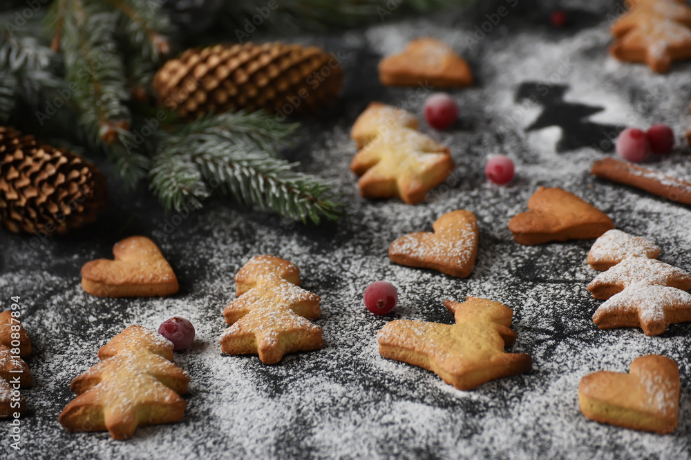 Homemade simple figurine cookies for the New Year and Christmas holiday against a dark background. branches of spruce, the atmosphere of preparation for the holiday and home comfort.
