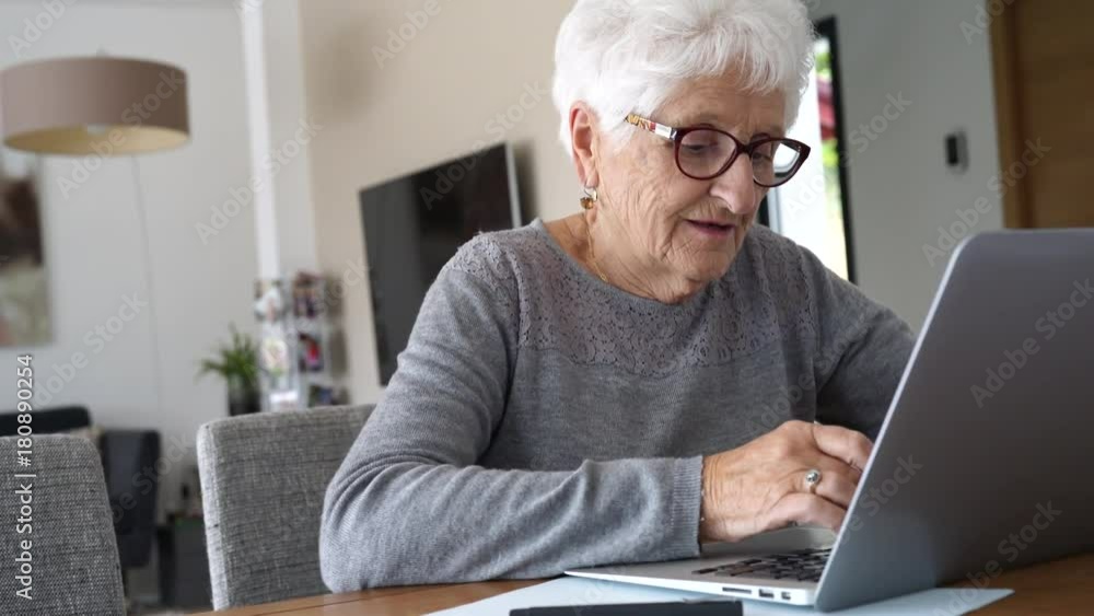 Old woman at home using laptop computer Old woman at home using laptop computer