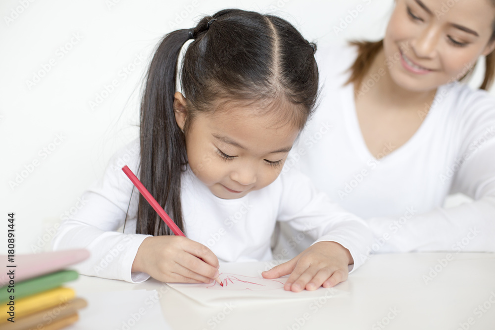 Attractive Little Girl writing Book. Mom Teaching her at home. Children Lifestyle, Education Concept. Attractive Little Girl writing Book. Mom Teaching her at home. Children Lifestyle, Education Concept.