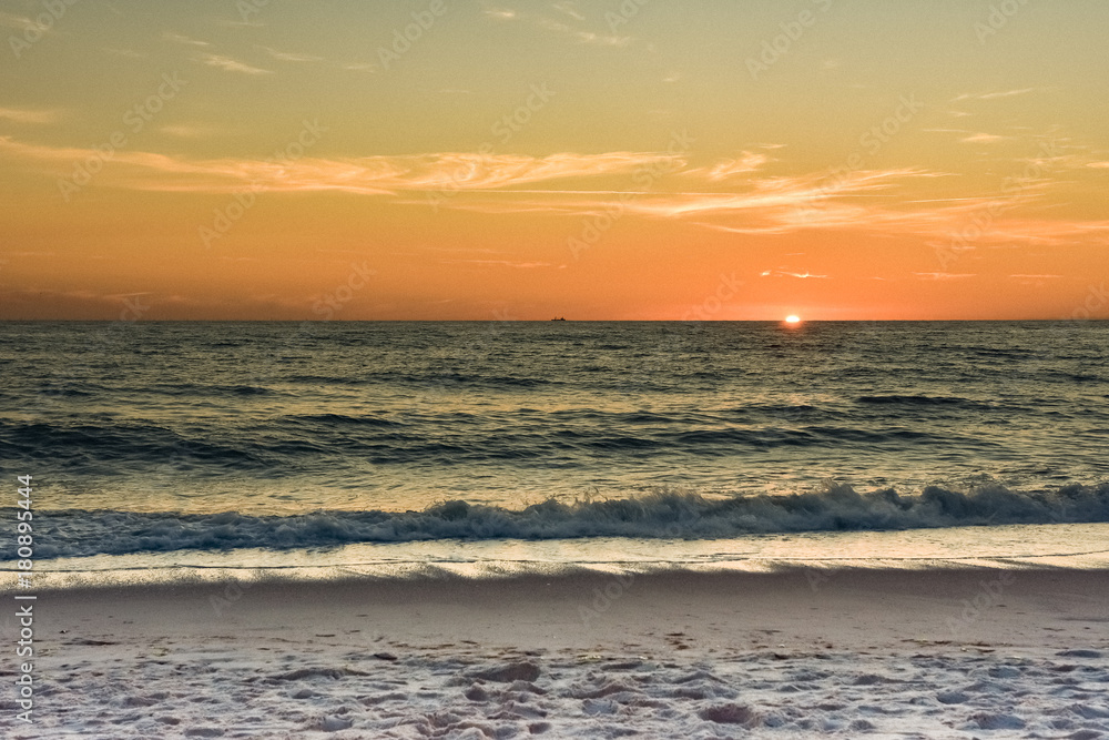 Sonnenuntergang in orange getaucht am Strand.