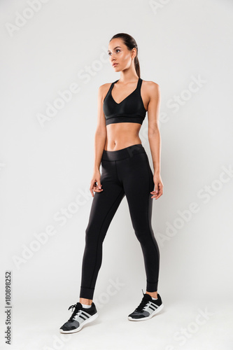 Young sports lady posing isolated over grey background.