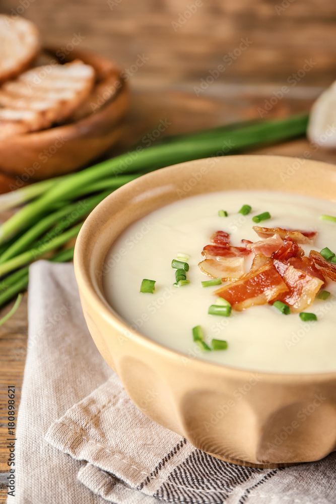 Bowl of yummy potato soup with bacon on wooden table Bowl of yummy potato soup with bacon on wooden table