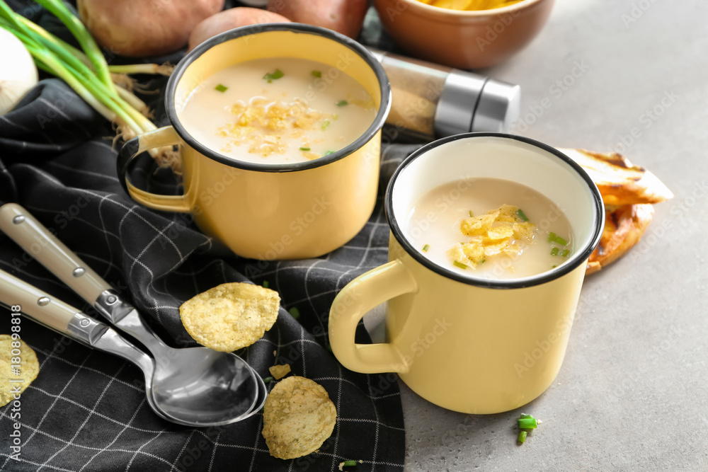 Mugs of yummy potato soup with crisps on table Mugs of yummy potato soup with crisps on table