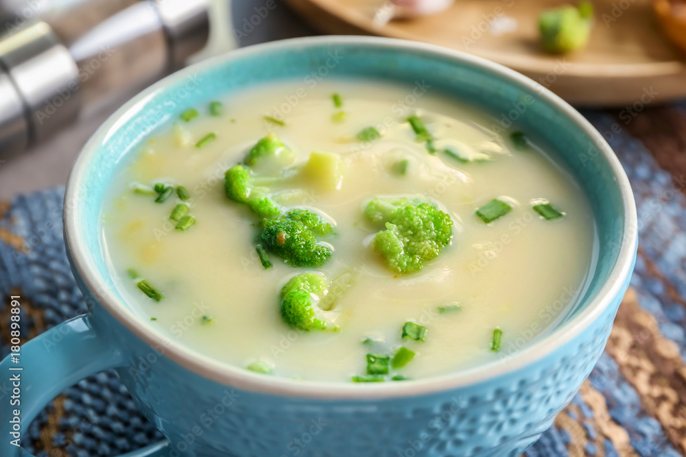 Cup of yummy potato soup with broccoli on table