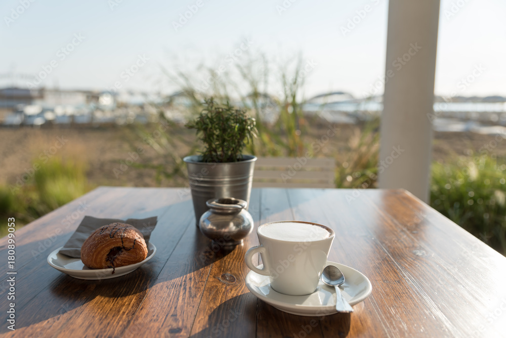 Breakfast of cappuccino and pastry at the beach