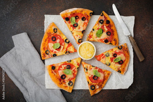 Pizza margarita with tomatoes, mazarella and slices of olives on a dark concrete or stone background. Traditional Italian cuisine. Selective focus. Top view. photo