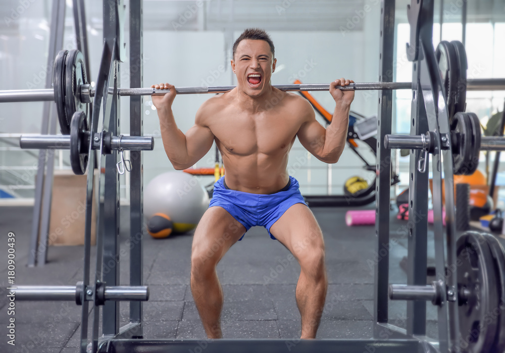 Fototapeta premium Muscular man training with barbell in gym