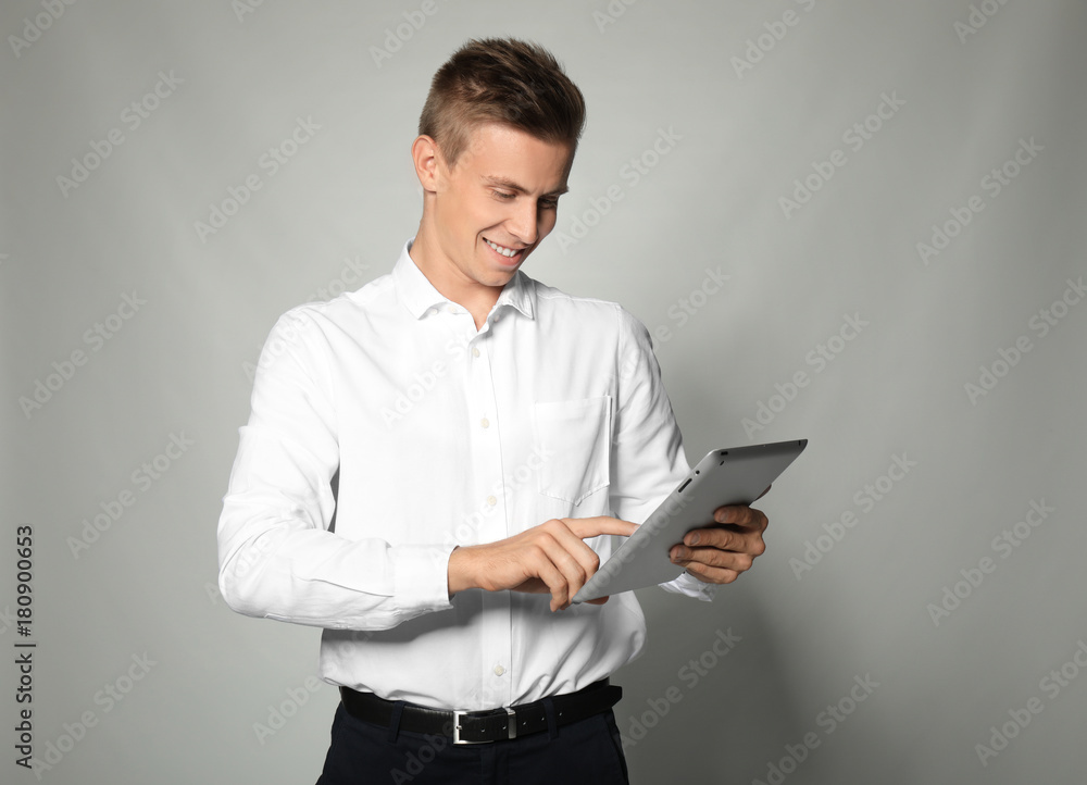 Attractive young manager with tablet on light background Attractive young manager with tablet on light background