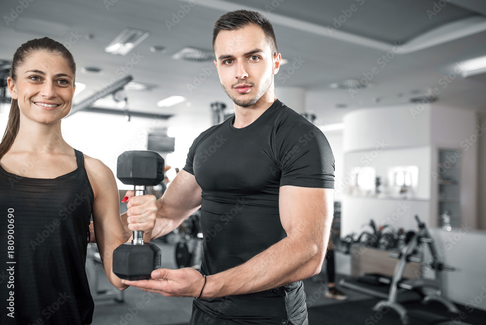Woman doing bicep curls in gym with her personal trainer Woman doing bicep curls in gym with her personal trainer