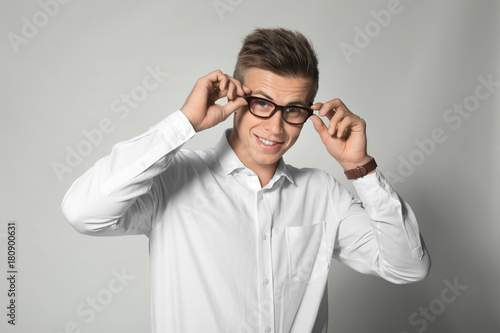 Attractive young manager wearing glasses on light background