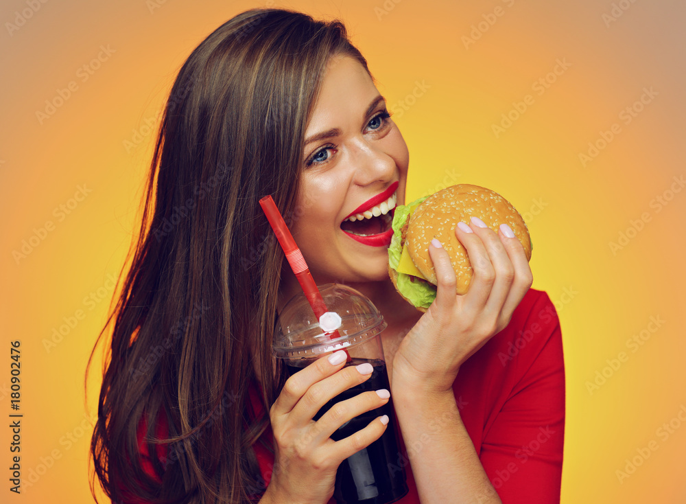 Pin up style portrait of smiling woman in red dress holding burger with cola drink.