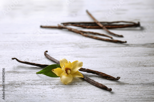 Dried vanilla pods and flower on wooden background