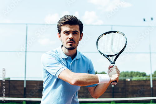 Another hit! Young handsome man playing tennis on the tennis court.  © MARIIA