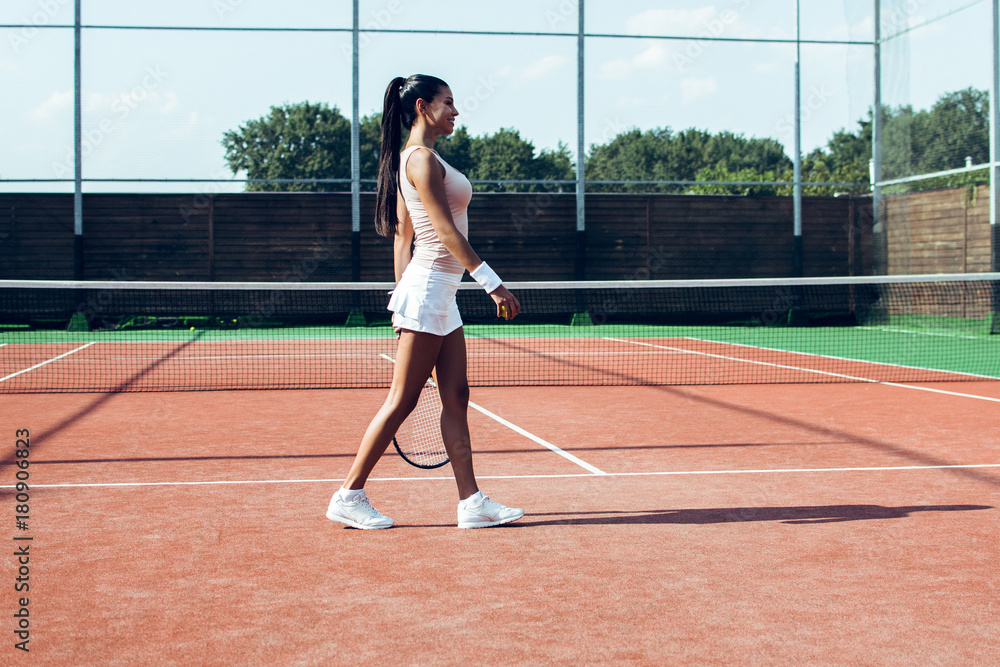 Way to victory. Side view full length of beautiful young woman standing on the tennis court. 